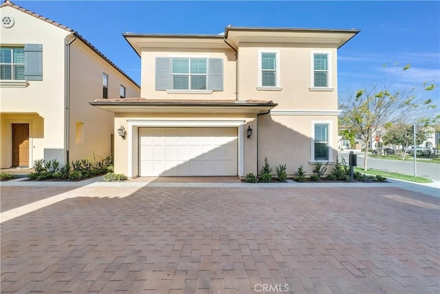 townhome / multi-family property with decorative driveway, an attached garage, and stucco siding