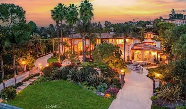 mediterranean / spanish-style home featuring a fire pit, a front lawn, and a tiled roof