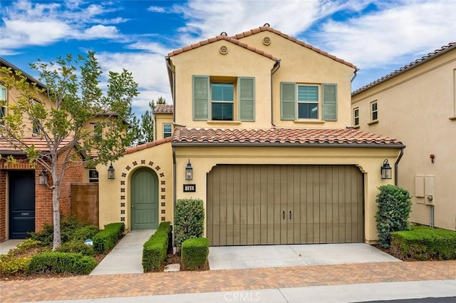 mediterranean / spanish house featuring decorative driveway, a tiled roof, and stucco siding