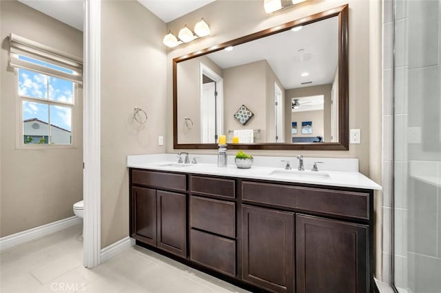 full bathroom with double vanity, a sink, toilet, and baseboards