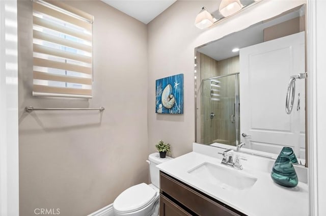 bathroom with toilet, a shower stall, and vanity