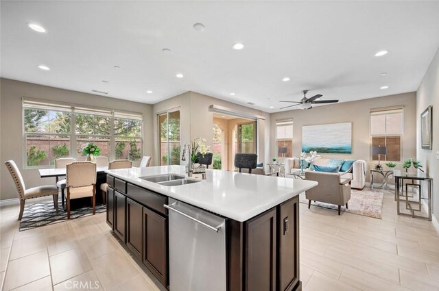 kitchen featuring light countertops, stainless steel dishwasher, a sink, and a healthy amount of sunlight