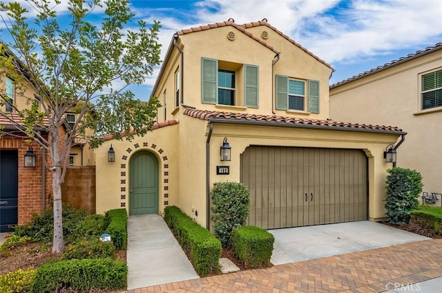 mediterranean / spanish-style house with decorative driveway, fence, a tiled roof, and stucco siding