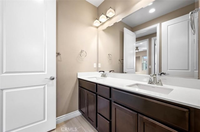 full bathroom with double vanity, a sink, and baseboards