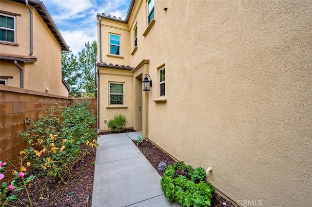 doorway to property featuring fence and stucco siding