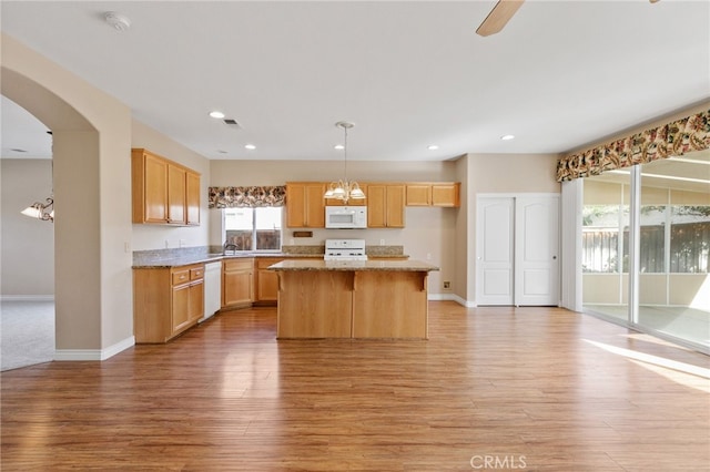 kitchen with white appliances, light hardwood / wood-style flooring, light stone counters, a center island, and decorative light fixtures