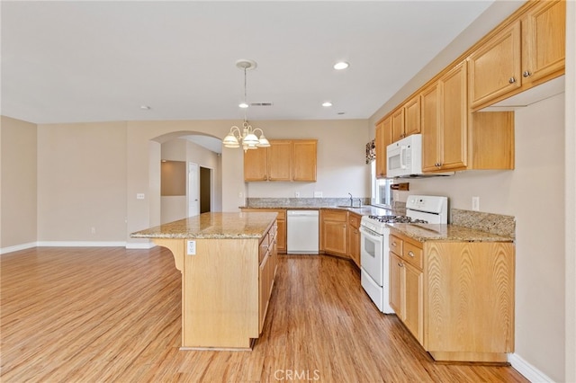 kitchen with white appliances, light wood-type flooring, pendant lighting, a kitchen island, and light stone countertops