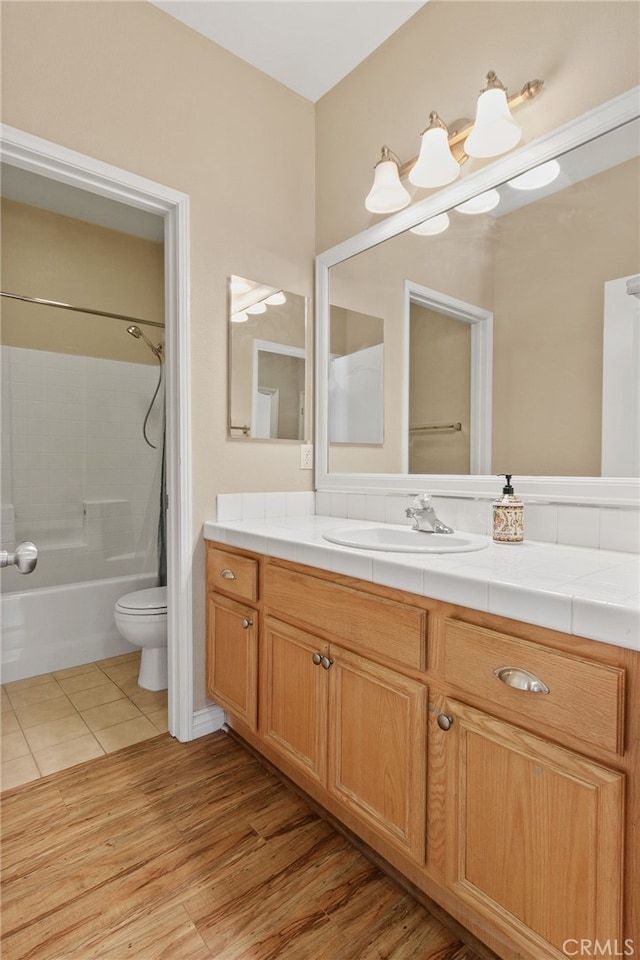 full bathroom featuring hardwood / wood-style flooring, vanity,  shower combination, and toilet