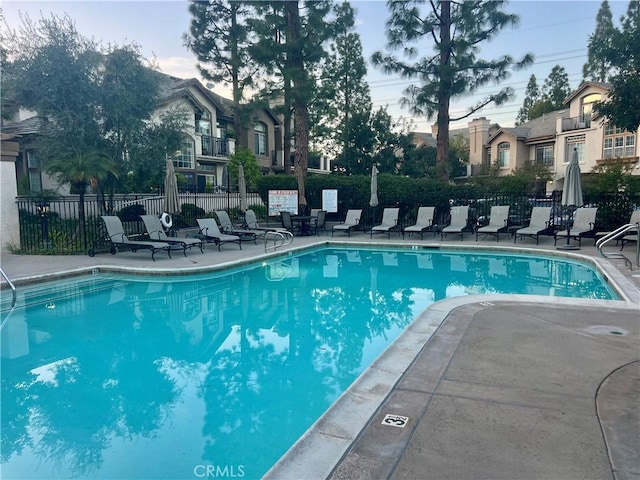 community pool with a patio area and fence