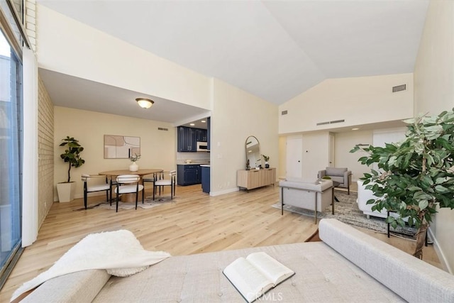 living room featuring high vaulted ceiling and light wood-type flooring