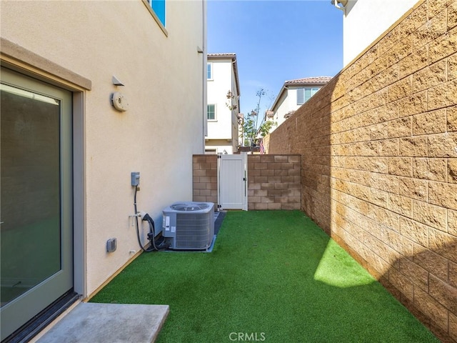 view of yard with fence, central AC unit, and a gate
