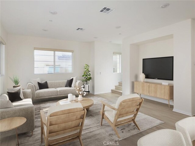 living area featuring visible vents, light wood-style flooring, and plenty of natural light