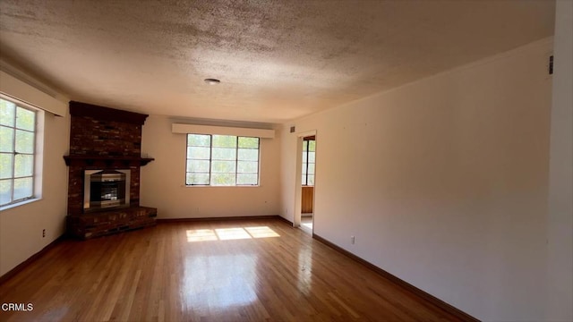 unfurnished living room with a fireplace, hardwood / wood-style floors, and a textured ceiling