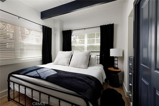 bedroom featuring hardwood / wood-style floors and beam ceiling