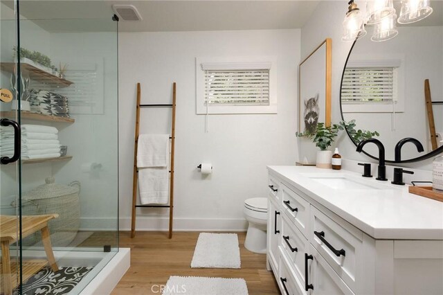 bathroom with vanity, toilet, hardwood / wood-style floors, and a shower
