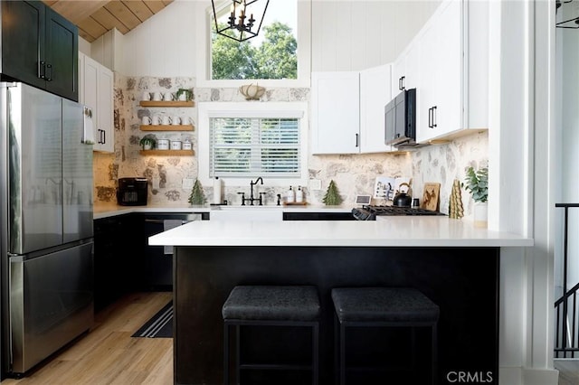 kitchen featuring sink, kitchen peninsula, stainless steel refrigerator, and black dishwasher