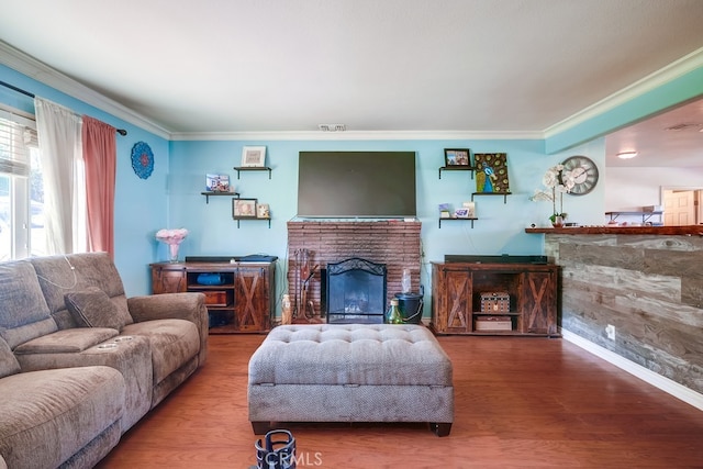 living area featuring a brick fireplace, crown molding, baseboards, and wood finished floors