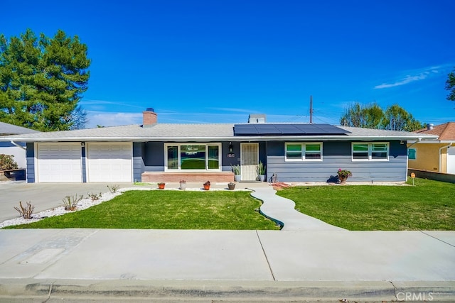 ranch-style house featuring an attached garage, roof mounted solar panels, and a front lawn