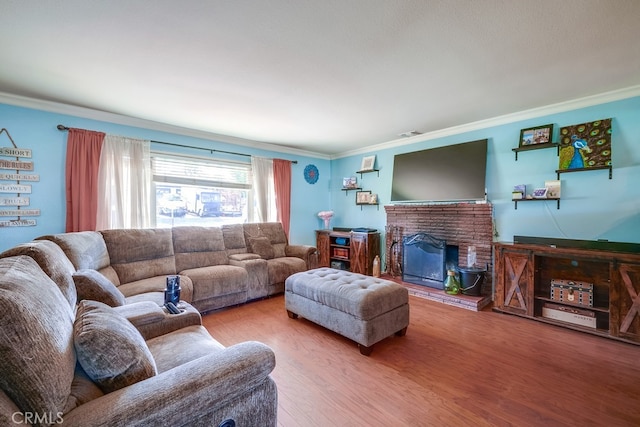 living area with ornamental molding, a brick fireplace, and wood finished floors