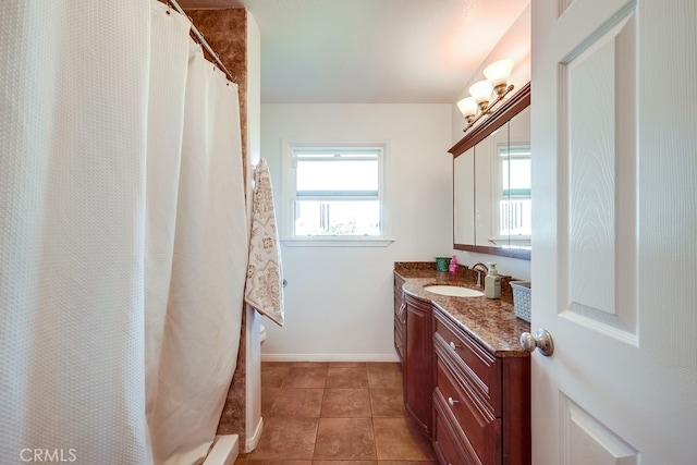 bathroom with tile patterned flooring, baseboards, vanity, and a shower stall