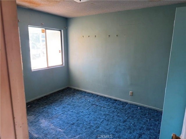 carpeted spare room featuring a textured ceiling and baseboards