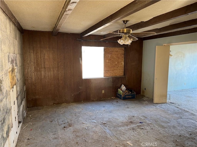 spare room with beam ceiling and a ceiling fan