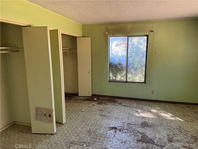 unfurnished bedroom featuring multiple closets and a textured ceiling