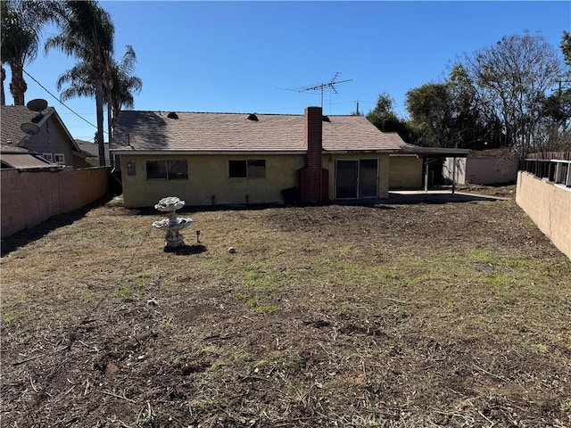 rear view of property with a fenced backyard, roof with shingles, and stucco siding