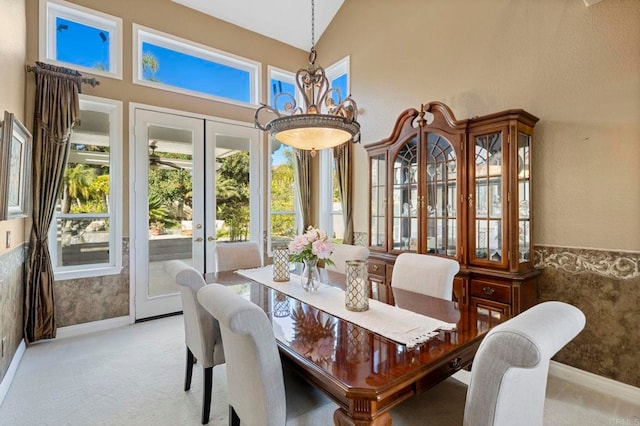 dining room featuring high vaulted ceiling, light colored carpet, and french doors