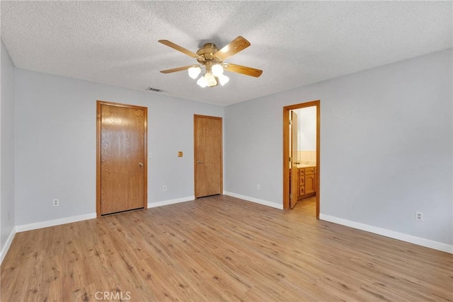 unfurnished bedroom featuring ceiling fan, light hardwood / wood-style floors, a textured ceiling, and ensuite bathroom