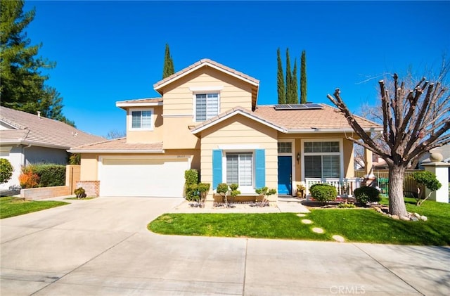 view of front facade featuring an attached garage, fence, concrete driveway, roof mounted solar panels, and a front yard