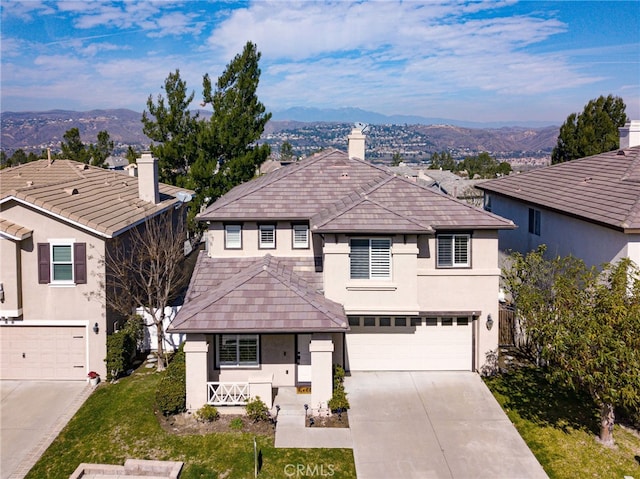 view of front of house with stucco siding, covered porch, an attached garage, a mountain view, and driveway