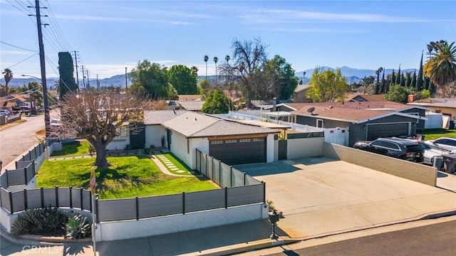 view of front facade featuring an attached garage, fence private yard, driveway, a residential view, and stucco siding