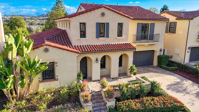 mediterranean / spanish house featuring decorative driveway, a tiled roof, and stucco siding