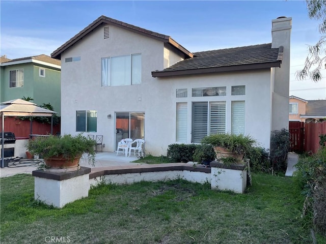 rear view of property featuring a gazebo, a patio, and a lawn