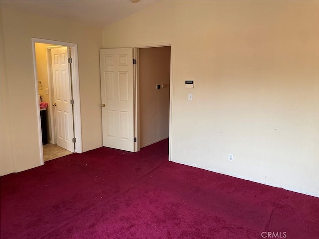 unfurnished bedroom featuring lofted ceiling, carpet floors, and ensuite bathroom