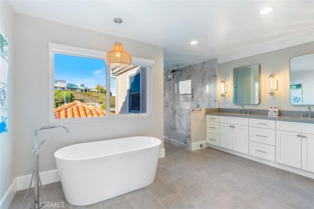 bathroom featuring a freestanding tub, a sink, baseboards, a marble finish shower, and double vanity