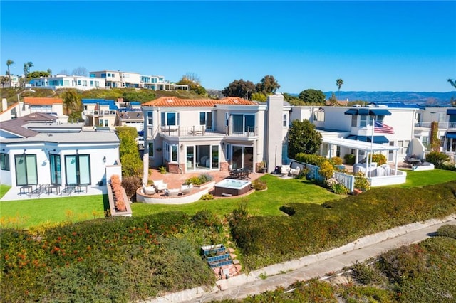 back of property with a residential view, a lawn, and a balcony