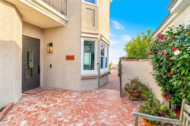 doorway to property with a patio area, fence, and stucco siding