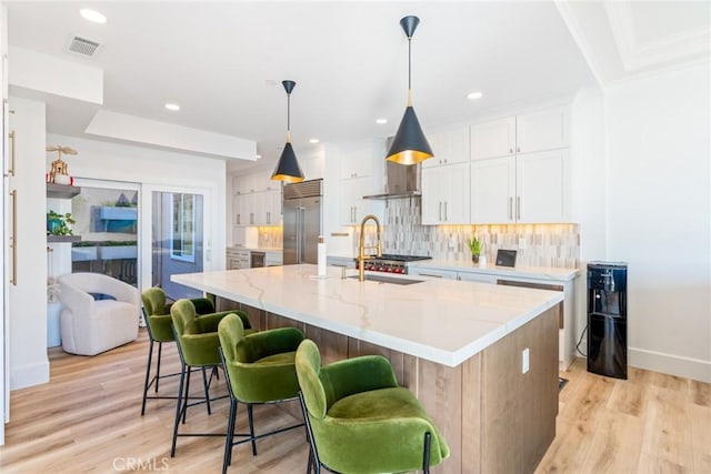 kitchen with a spacious island, visible vents, white cabinets, hanging light fixtures, and stainless steel built in fridge