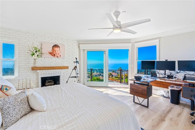 bedroom with a ceiling fan, a brick fireplace, light wood-style flooring, and crown molding