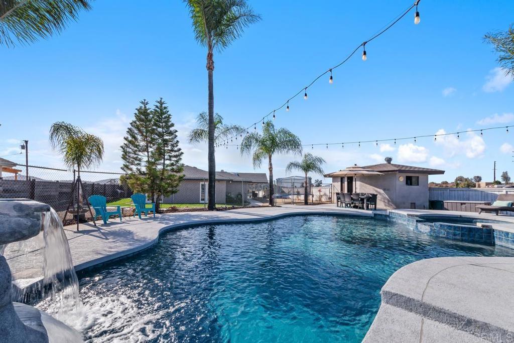 view of pool featuring a pool with connected hot tub, fence, and a patio