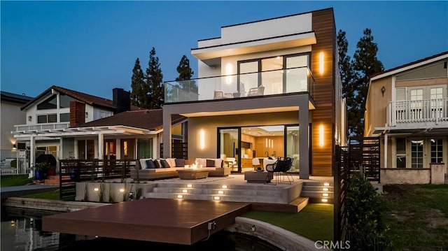 rear view of property with an outdoor hangout area and a balcony