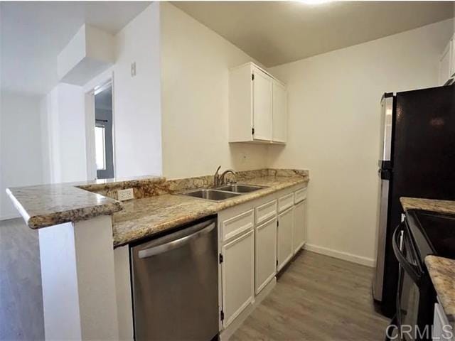 kitchen featuring sink, white cabinetry, light hardwood / wood-style flooring, stainless steel dishwasher, and kitchen peninsula