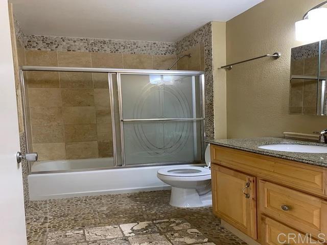 full bathroom with vanity, toilet, and combined bath / shower with glass door