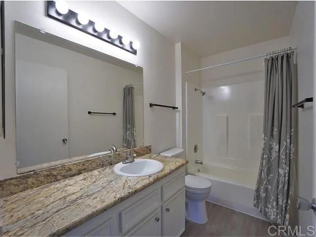 full bathroom with shower / tub combo with curtain, vanity, hardwood / wood-style floors, and toilet