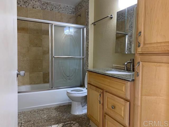 full bathroom with vanity, toilet, and combined bath / shower with glass door