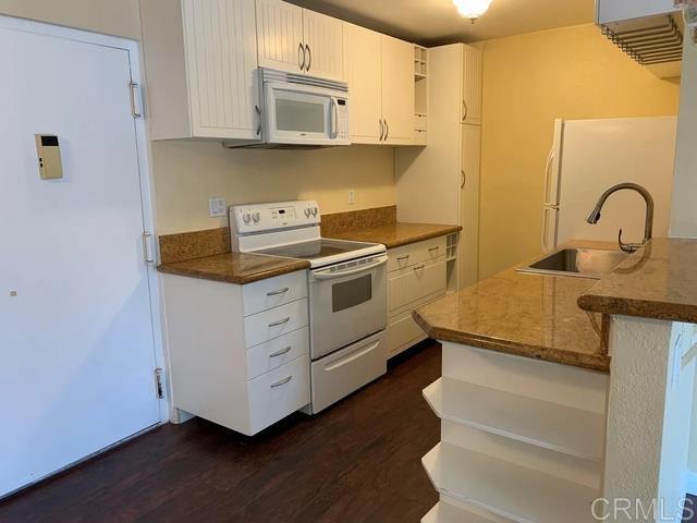 kitchen featuring sink, white appliances, dark wood-type flooring, white cabinetry, and kitchen peninsula