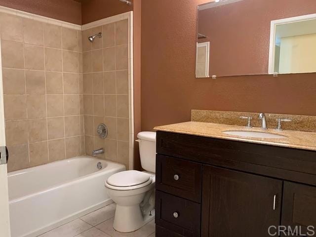 full bathroom with tile patterned flooring, vanity, tiled shower / bath combo, and toilet