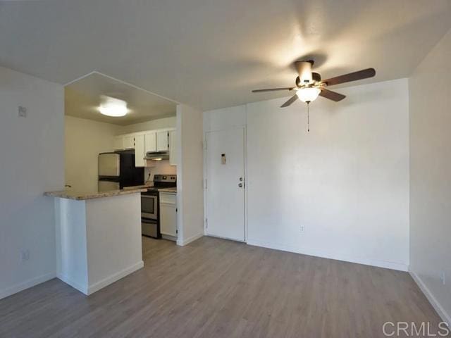 kitchen with electric stove, white cabinetry, light hardwood / wood-style flooring, and black refrigerator